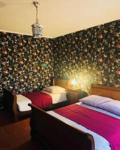 2 camas en una habitación con papel pintado floral en La Babayaga, en Capestang