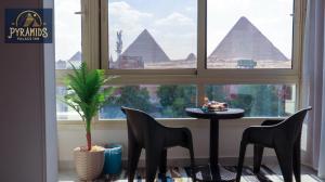 een tafel en stoelen voor een raam met piramides bij Pyramids Palace Inn in Caïro