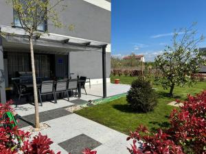 a patio with a picnic table in a garden at Capsula Luxury Apartment Umag in Umag