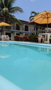 a large swimming pool with chairs and umbrellas at Pousada Solar da Praia in Tamandaré