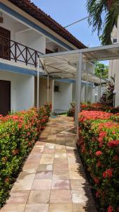 a walkway in front of a building with red flowers at Pousada Solar da Praia in Tamandaré