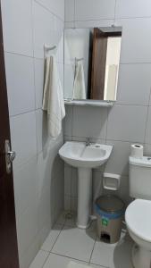 a white bathroom with a sink and a toilet at Pousada Solar da Praia in Tamandaré