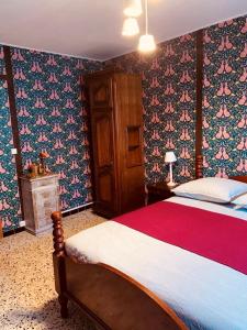 - une chambre avec un grand lit et du papier peint floral dans l'établissement La Babayaga, à Capestang