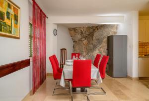 uma sala de jantar com uma mesa e cadeiras vermelhas em Villa Sara em Vinišće