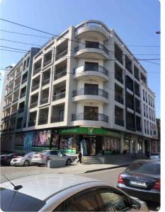 un gran edificio blanco con coches estacionados frente a él en central square, en Kutaisi