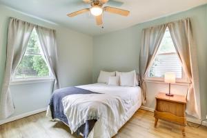 a bedroom with a bed with a ceiling fan and two windows at Centrally Located Gonzales Home with Yard! in Gonzales