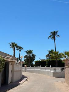 podjazd z palmami i białym płotem w obiekcie Bungalow Aguas Nuevas Costa del Cezar w mieście Torrevieja
