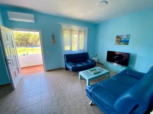 a blue living room with a couch and a tv at White & Blue Apartment's in Golem