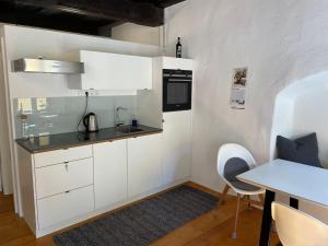 cocina con armarios blancos y mesa en Kleine Residenz en Weiden