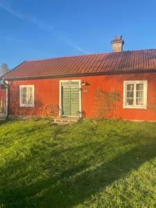 a red house with a green door in a yard at Skäret in Åkerö