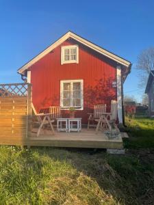 a red barn with chairs and a porch at Skäret in Åkerö