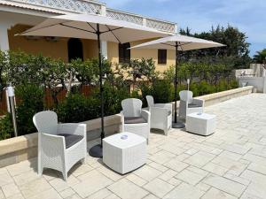 a group of chairs and umbrellas on a patio at Allivigne Rooms & Pool in Polignano a Mare