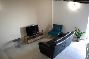 sala de estar con sofá de cuero y TV en IL CORTILE DELLE ZAGARE, en Pollica