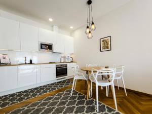 cocina con armarios blancos, mesa y sillas en Rotermann City Apartments Roseni en Tallin