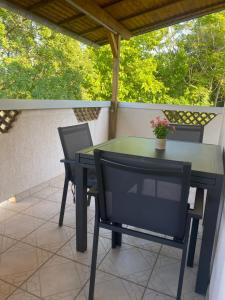 a glass table and two chairs on a patio at Studio Lokvica in Omišalj