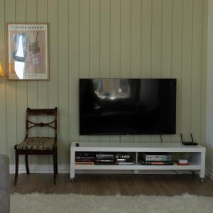 a television on a white entertainment center with a chair at Sentralt og romslig i Kristiansand sentrum in Kristiansand