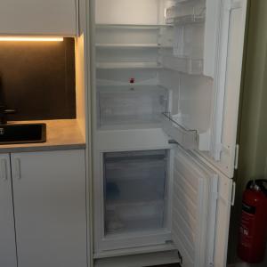 an empty refrigerator with its door open in a kitchen at Sentralt og romslig i Kristiansand sentrum in Kristiansand