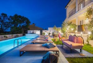 a pool with tables and couches next to a building at Vinkuran Residence - Adults Only in Pula