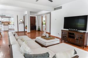 uma sala de estar com um sofá branco e uma televisão de ecrã plano em Daria Beachfront community steps 2 pool- Generator em Sabana