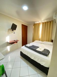 アラクルスにあるBuriti Hotel - Barra do Riacho, Aracruz ESのベッドとテレビ付きのホテルルーム