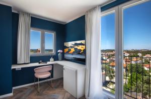 Zimmer mit blauen Wänden und einem Schreibtisch mit Fenster in der Unterkunft Vinkuran Residence - Adults Only in Pula