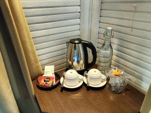 un tavolo con bollitore per tè, tazze e una bottiglia di Balangan Surf Resort a Jimbaran