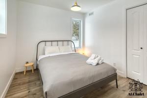 a bedroom with a bed with white sheets and a window at Le Loonix- Chalet familiale avec Spa in Petite-Rivière-Saint-François