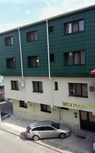 a car parked in front of a green and white building at West Plaza Residence in Bucharest