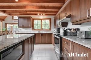 a kitchen with wooden cabinets and granite counter tops at B-Évasion Chalet avec spa sauna in Petite-Rivière-Saint-François