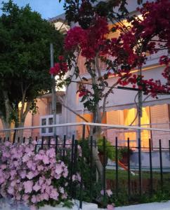 een hek met roze bloemen voor een gebouw bij Vicky's Guesthouse in Kavos