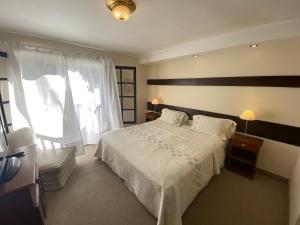 a bedroom with a white bed and a window at Hosteria del Bosque in Necochea