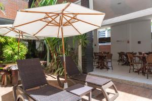eine Terrasse mit 2 Stühlen und einem Sonnenschirm in der Unterkunft Ritz Plazamar Hotel in Maceió