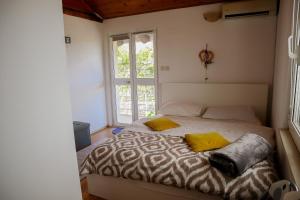 a bed with two yellow pillows in a room with a window at Guest House Godimento in Čilipi