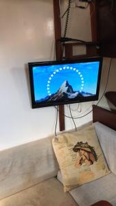 uma televisão de ecrã plano sentada numa parede ao lado de um sofá em Yacht - no shower em Arefjord