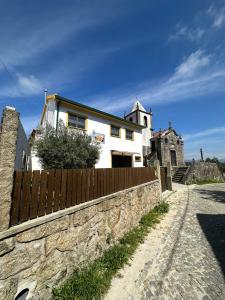 ein weißes Haus hinter einer Steinmauer mit einem Zaun in der Unterkunft Casa Da Serra in Oliveira de Frades