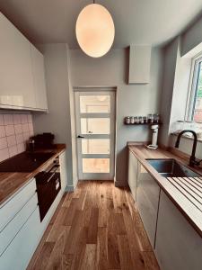 a kitchen with white cabinets and a wooden floor at Chic Family Home Near Parks & Leicester Uni in Leicester