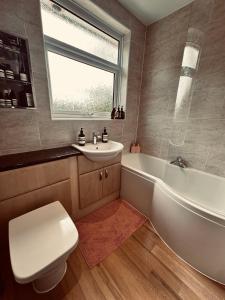 a bathroom with a tub and a toilet and a sink at Chic Family Home Near Parks & Leicester Uni in Leicester