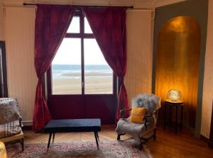 ein Wohnzimmer mit einem Fenster mit Blick auf den Strand in der Unterkunft Appartement exception avec vue sur mer imprenable in Lion-sur-Mer