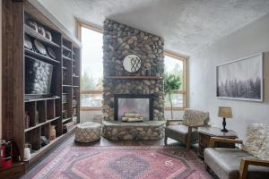 a living room with a stone fireplace with a clock at Wapiti View 6-Bedroom Cabin 28mins to Yellowstone in Island Park