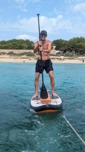 a man standing on a paddle board in the water at Alójate en un Velero en Ibiza in Illes Balears