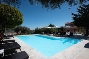 une grande piscine avec des chaises longues et des parasols dans l'établissement Eliathos Residence Houses, à Archanes