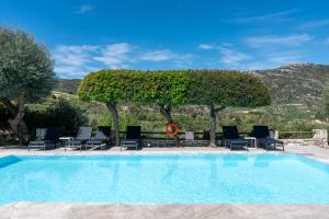 une grande piscine avec des chaises et des arbres dans l'établissement Eliathos Residence Houses, à Archanes