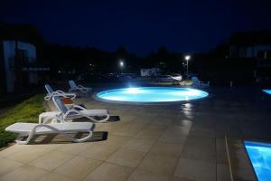 a swimming pool at night with lounge chairs around it at Apartament 12 in Żarnowska