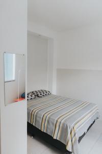 - une chambre blanche avec un lit et un miroir dans l'établissement Recanto Kitnet, à Lagoa Santa