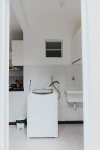 uma cozinha branca com um lavatório e um frigorífico branco em Recanto Kitnet em Lagoa Santa