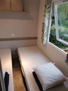 Habitación pequeña con cama y ventana en Mobilhome climatisé 3 chambres 6 pers cosy au vert en bordure de l'Eure JO2024, en Ivry-la-Bataille
