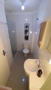 a white bathroom with a toilet and a sink at Apto climatizado 502, apenas 5 min das Thermas in Piratuba