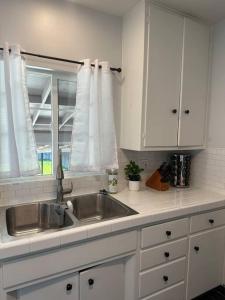 Una cocina blanca con fregadero y ventana. en Modern La Cresta, en Bakersfield 19 fotos más