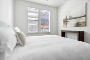 une chambre blanche avec un grand lit et deux fenêtres dans l'établissement Kasa At Artisan Music Row Nashville, à Nashville