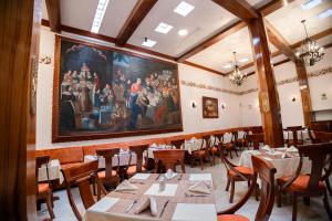 una sala da pranzo con tavoli e un dipinto sul muro di Hotel Hacienda Cusco Plaza a Cuzco